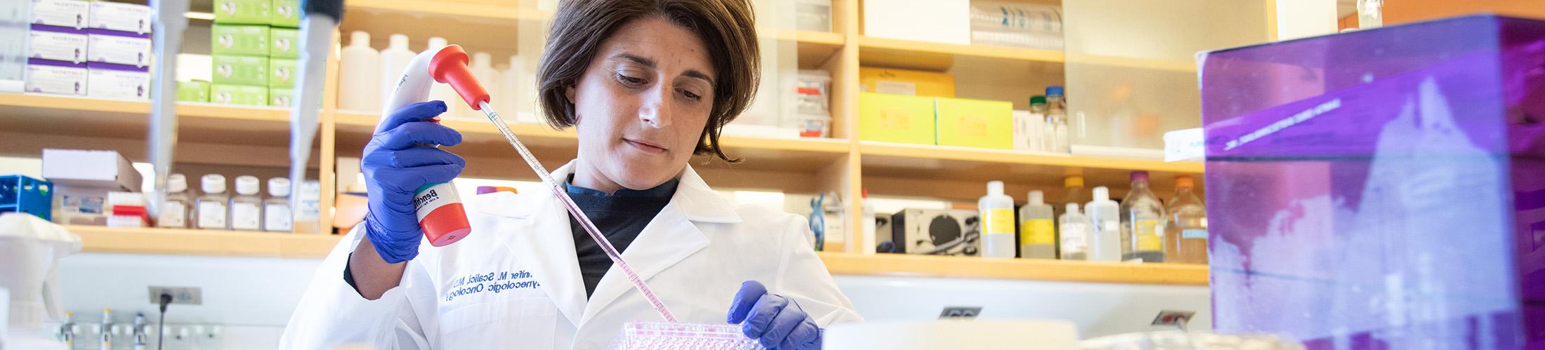 Professor working in lab holding a dropper.